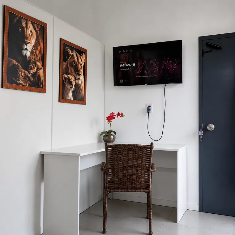 Interior de apartamento com bancada de trabalho, cadeira e televisão