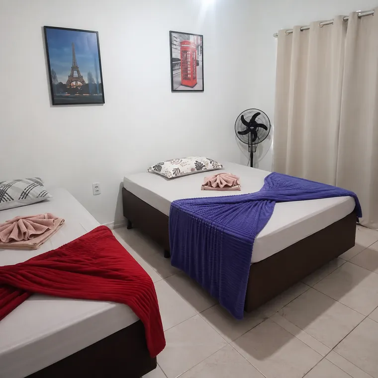 Quarto da casa com duas camas de casal e cortina